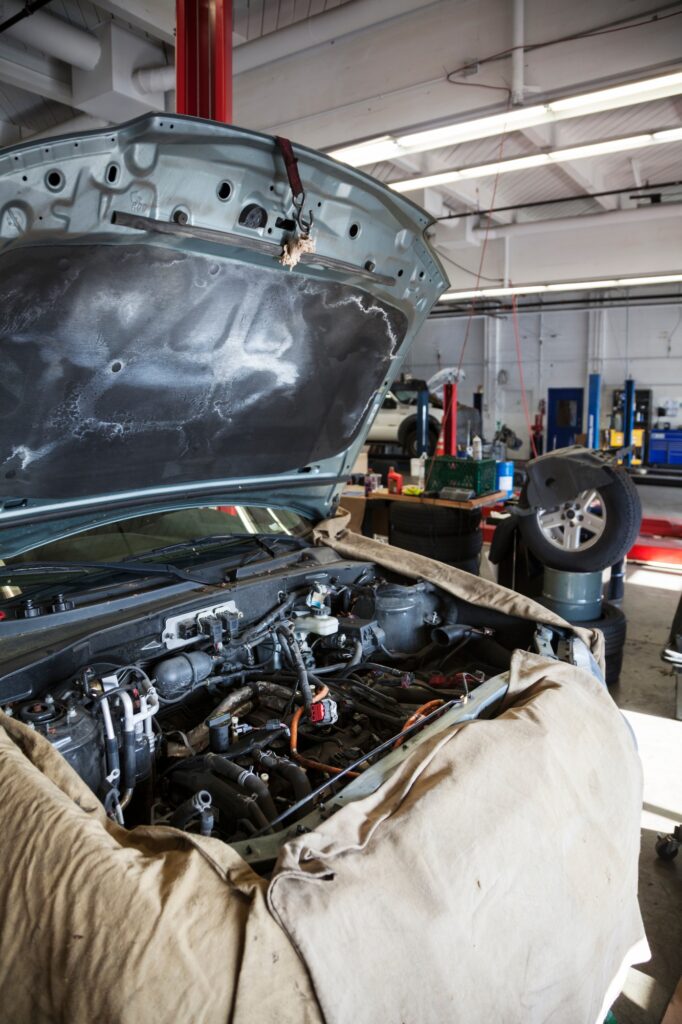 Open engine compartment of a car draped and ready for a mechanic in auto repair shop